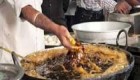 آشپزی که غذای در حال پخت را با دستش بهم هم میزند +عکس